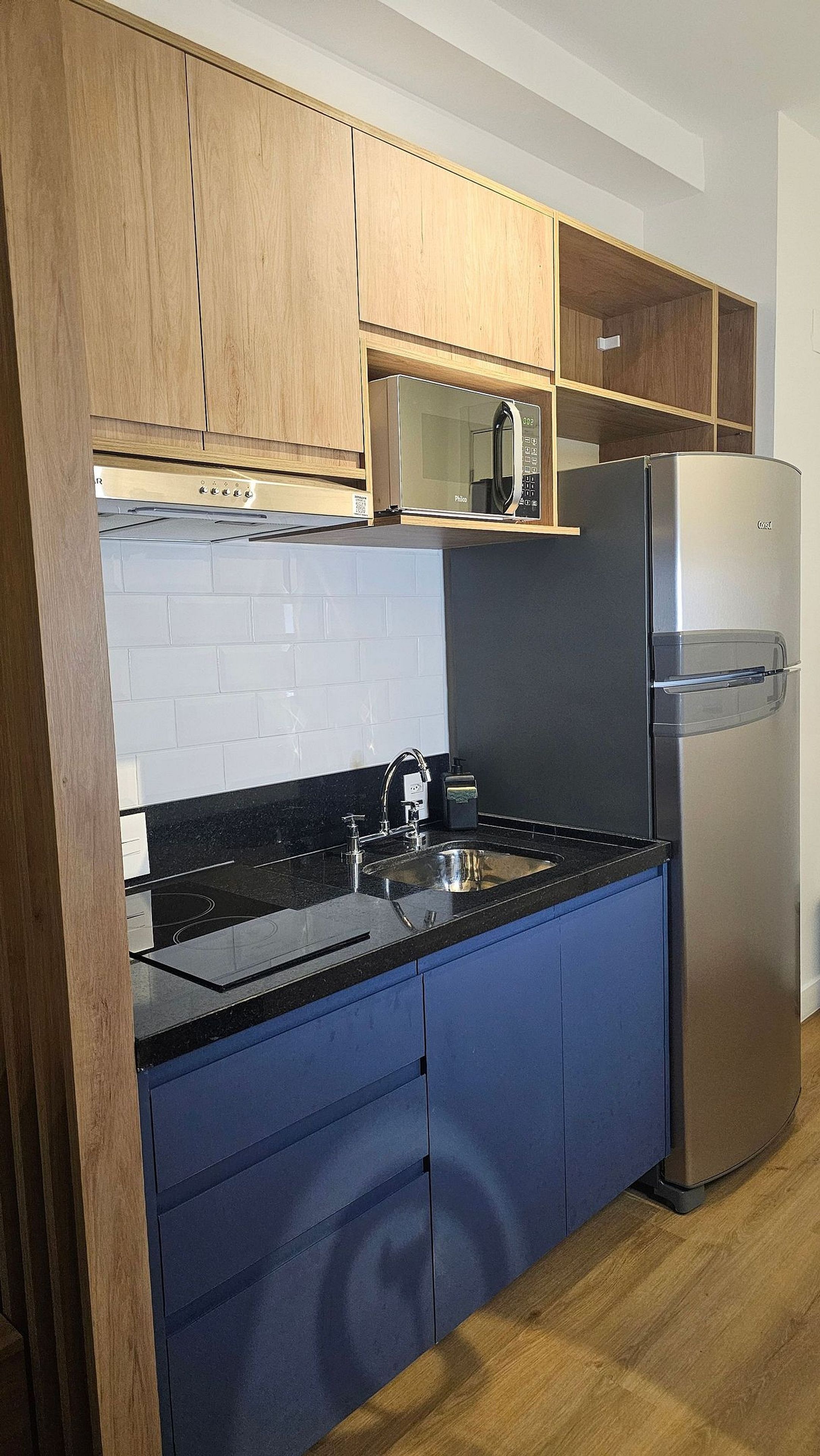 Una cocina con encimera negra, electrodomésticos de acero inoxidable y armarios de madera.
