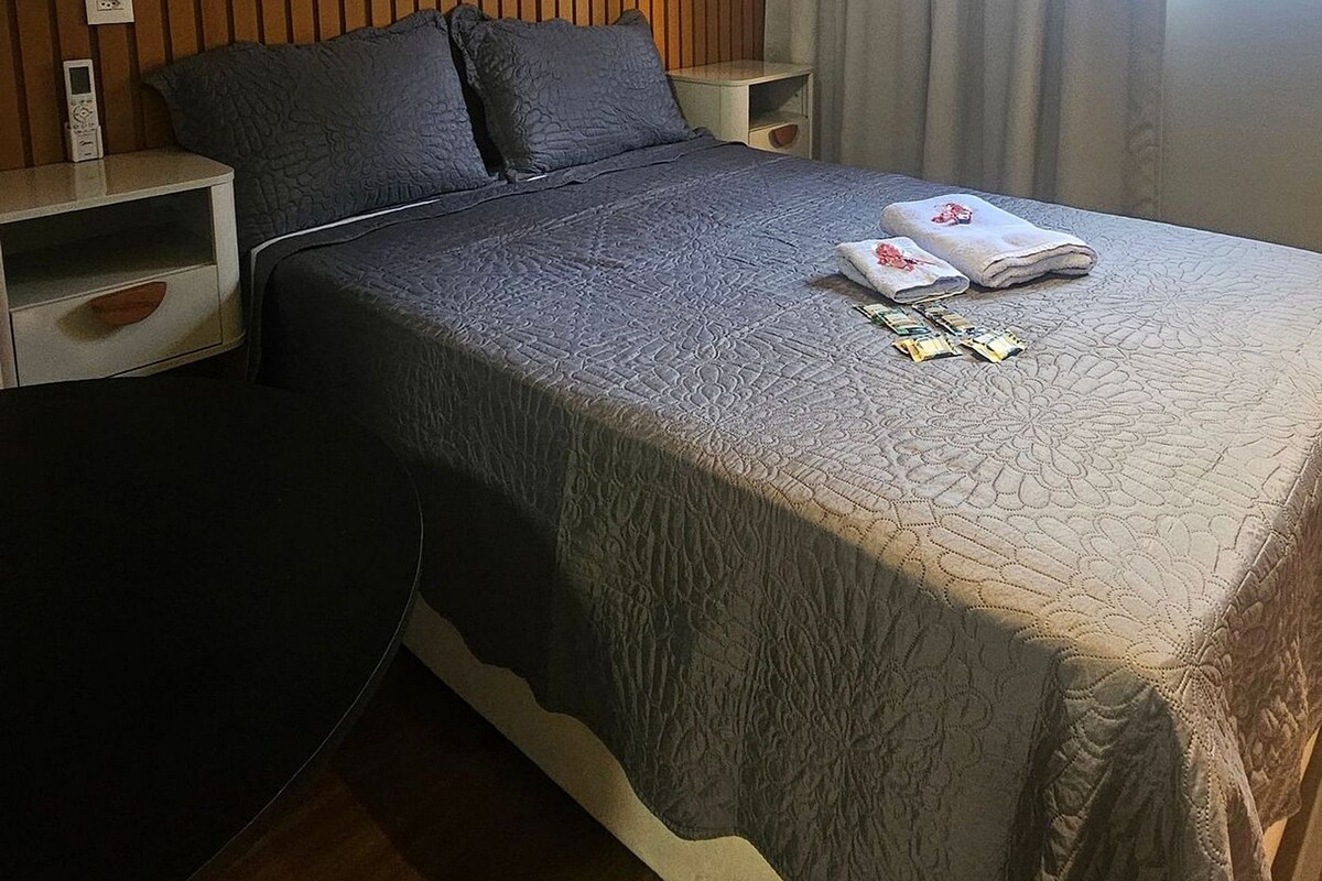 Quarto de hotel com cama, mesas de cabeceira, cortinas e obras de arte nas paredes.