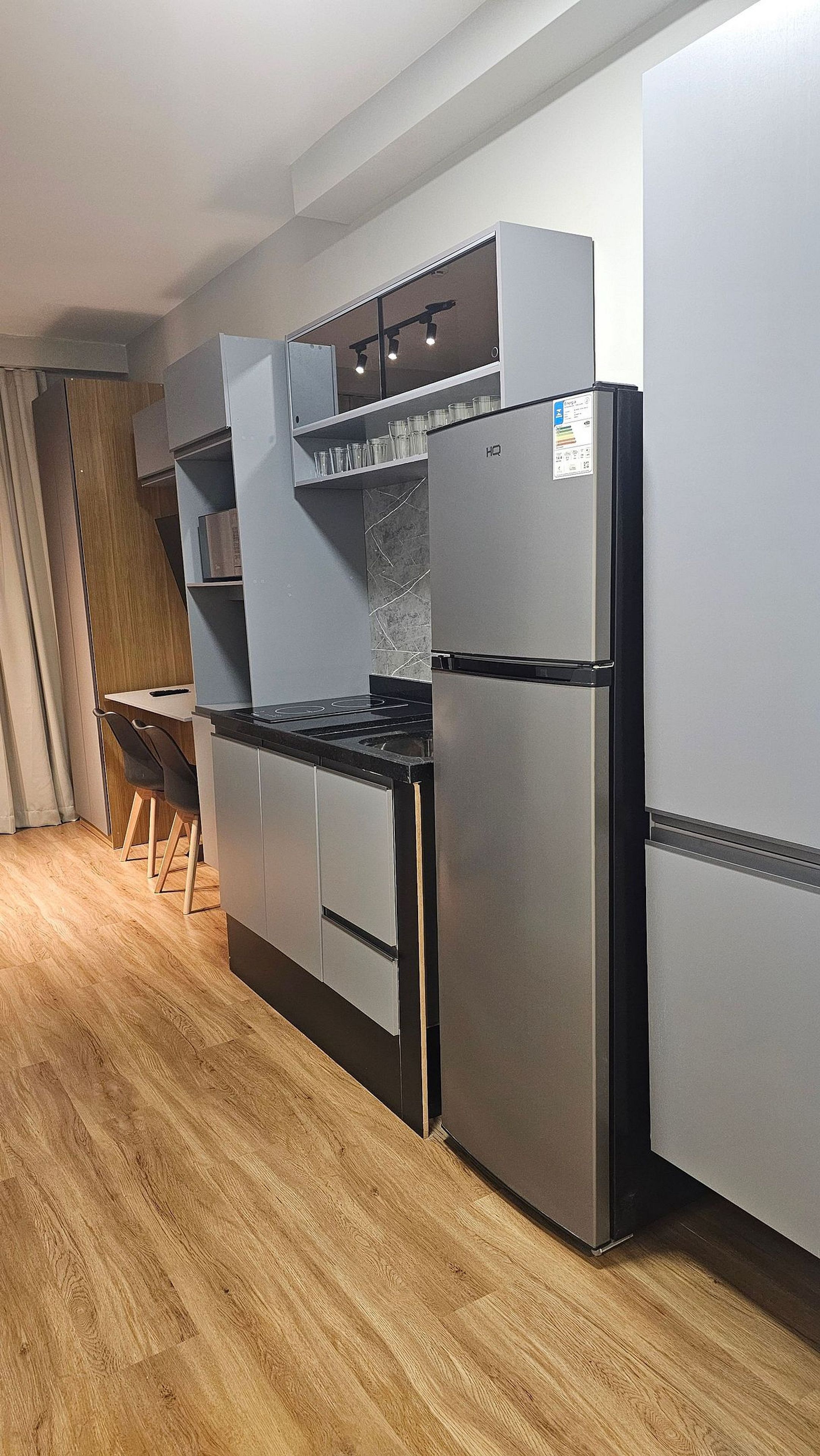 Eine kompakte Küche mit Einbauofen, Kühlschrank und Mikrowelle. Es gibt einen Essbereich mit Tisch und Stühlen.