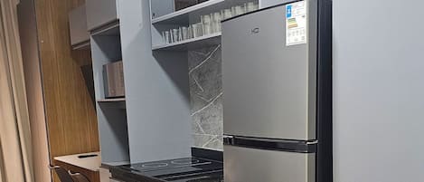 A compact kitchen with a built-in oven, a refrigerator, and a microwave. There is a dining area with a table and chairs.