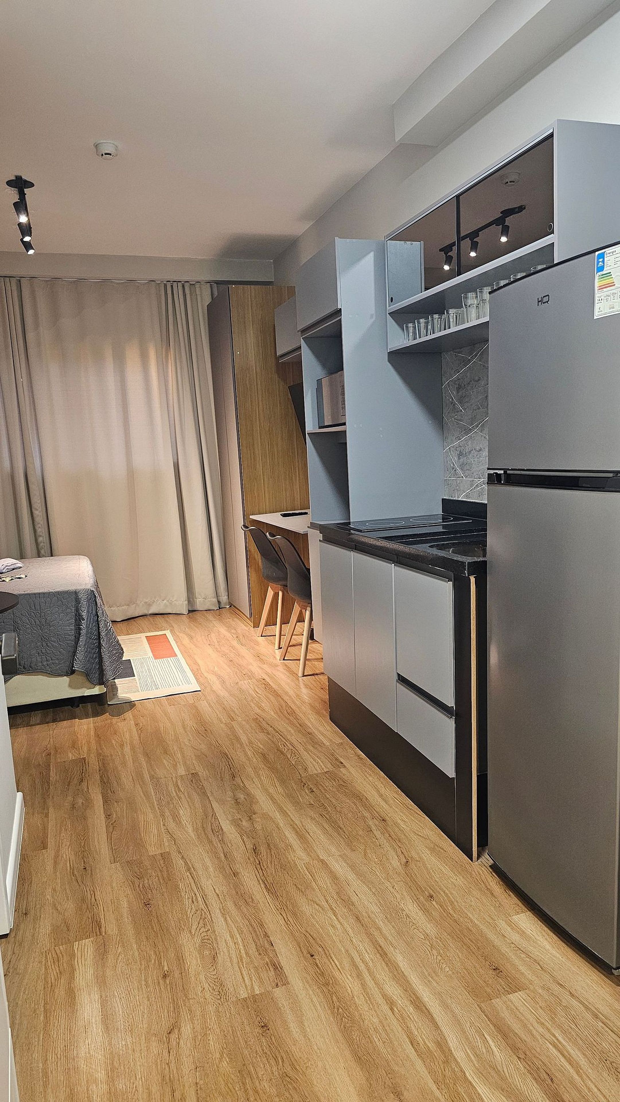 Een kleine keuken met een ingebouwde kookplaat, een koelkast en een eethoek met een tafel en stoelen.