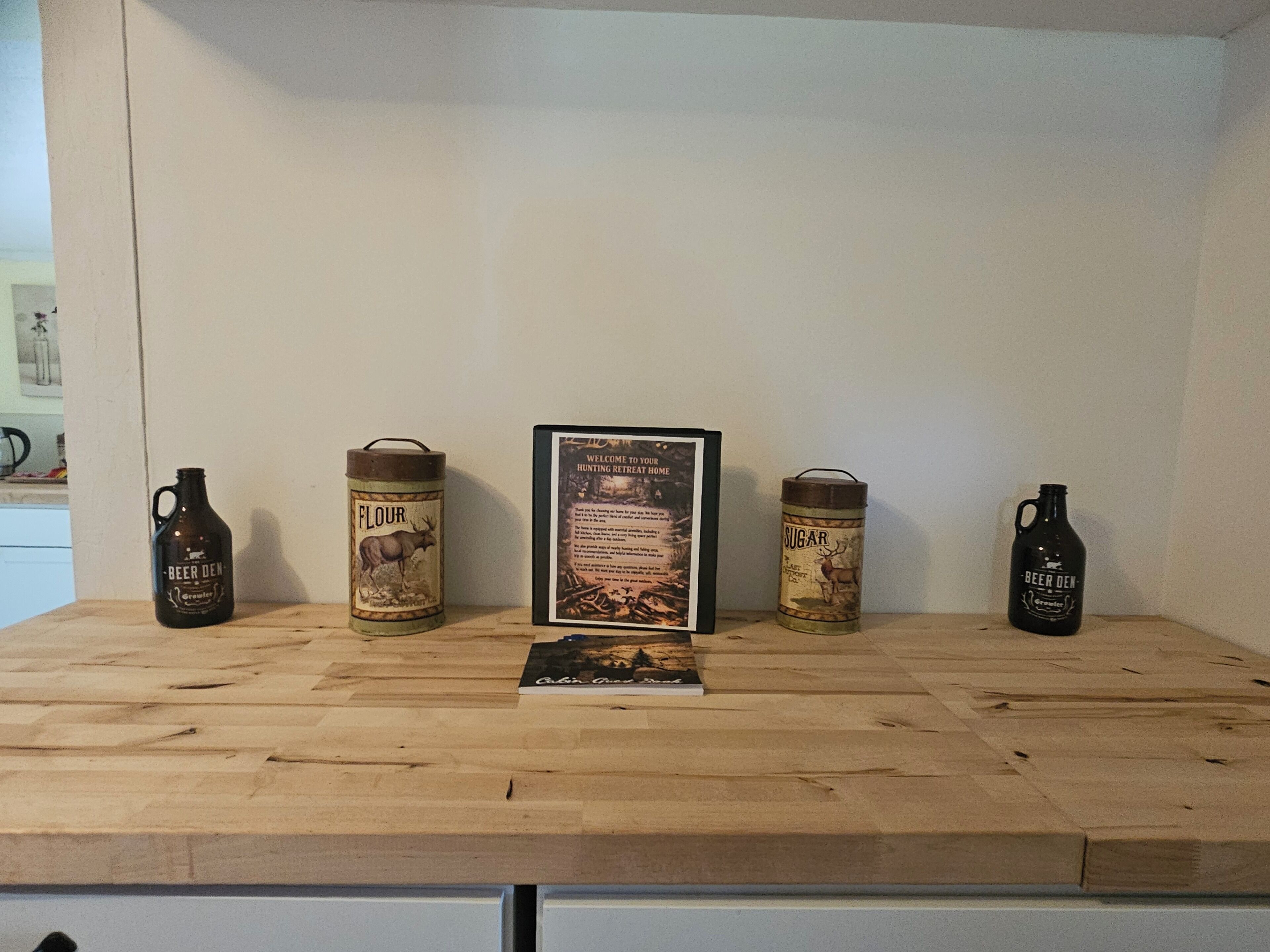 A wooden table with four vintage beer kegs and a framed welcome sign.