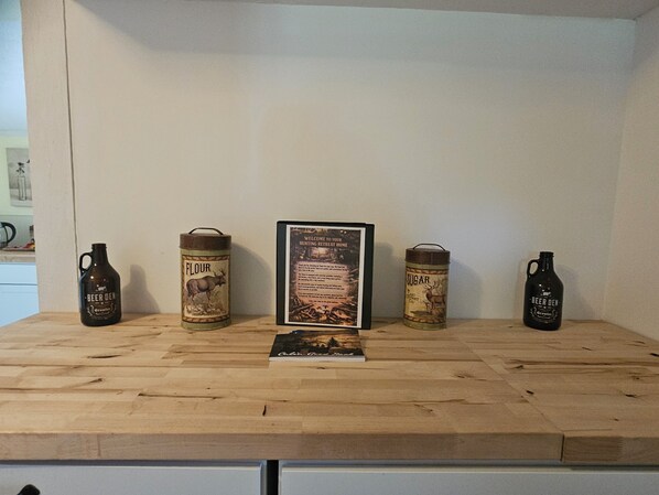 A wooden table with four vintage beer kegs and a framed welcome sign.