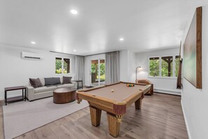 A modern living room with a pool table, a sofa, and a lamp.