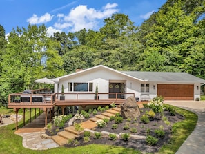A modern two-story house with a covered deck, a garage, and a landscaped garden with stepping stones.