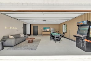 A modern living room with a sofa, coffee table, and a dining area with chairs and a table.