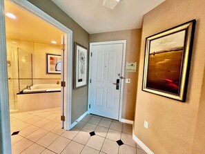 A hallway with a white door, a framed picture on the wall, and a bathroom visible through an open door. - MGM Signature Deluxe Suite • Strip, Sphere & F1 Track Views • No Resort Fee (Las Vegas)