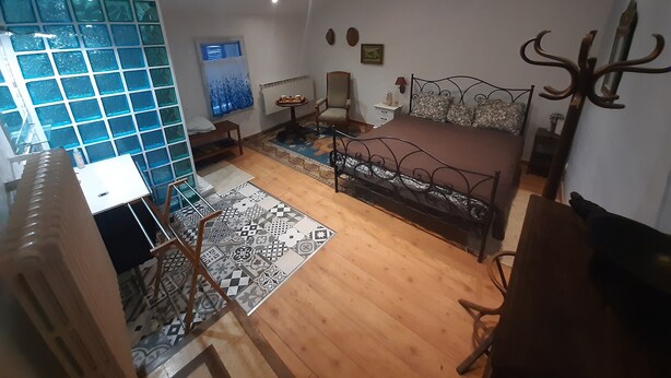 A bedroom with a bed, a chair, a small table, a radiator, and a ceiling fan. - Charming village house in the heart of the Luberon—a typical village house in the Luberon region (Grambois)