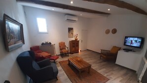 A living room with a sofa, armchair, coffee table, and a television. - Charming village house in the heart of the Luberon—a typical village house in the Luberon region (Grambois)