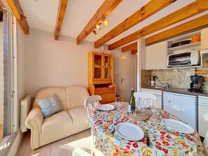 Un coin repas chaleureux avec une nappe à motifs floraux, un canapé et un meuble en bois.