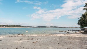 Una playa con agua cristalina, un bote y una costa lejana.
