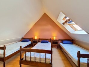 A triangular attic bedroom with three beds, each with a wooden headboard, and a skylight. - Carnac - 3-room duplex apartment - 26m² (CARNAC)