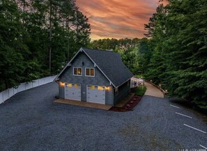 Ein zweistöckiges Haus mit Kiesweg, überdachter Veranda und Blick auf einen bewaldeten Bereich.