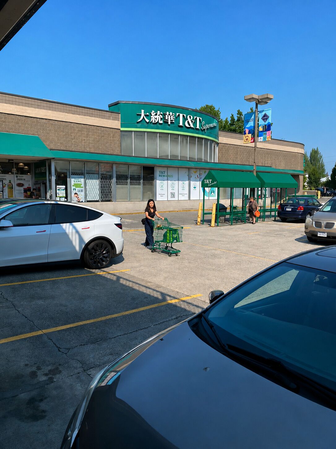 A T&T Supermarket with a green awning and a person pushing a shopping cart.