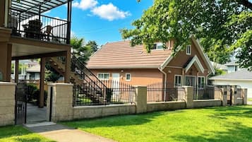 A residential property with a covered patio, a fenced yard, and a two-story house with a sloped roof.