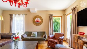 A living room with a sofa, armchair, and a dining table. - La Ferme de la Galoppaz (THOIRY)