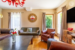 A living room with a sofa, armchair, and a dining table. - La Ferme de la Galoppaz (THOIRY)