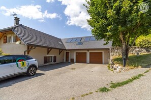 A two-story house with a garage, a driveway, and a tree. - La Ferme de la Galoppaz (THOIRY)