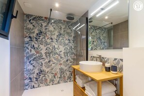 Ein modernes Badezimmer mit Dusche, Waschbecken und Spiegel.