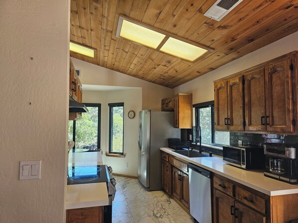 A kitchen with wooden cabinets, a stainless steel refrigerator, a microwave, and a coffee maker.
