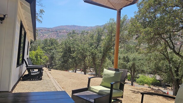 An outdoor seating area with wicker furniture and a view of a forested hillside.