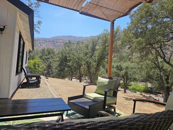 An outdoor seating area with wicker furniture and a view of a forested hillside.