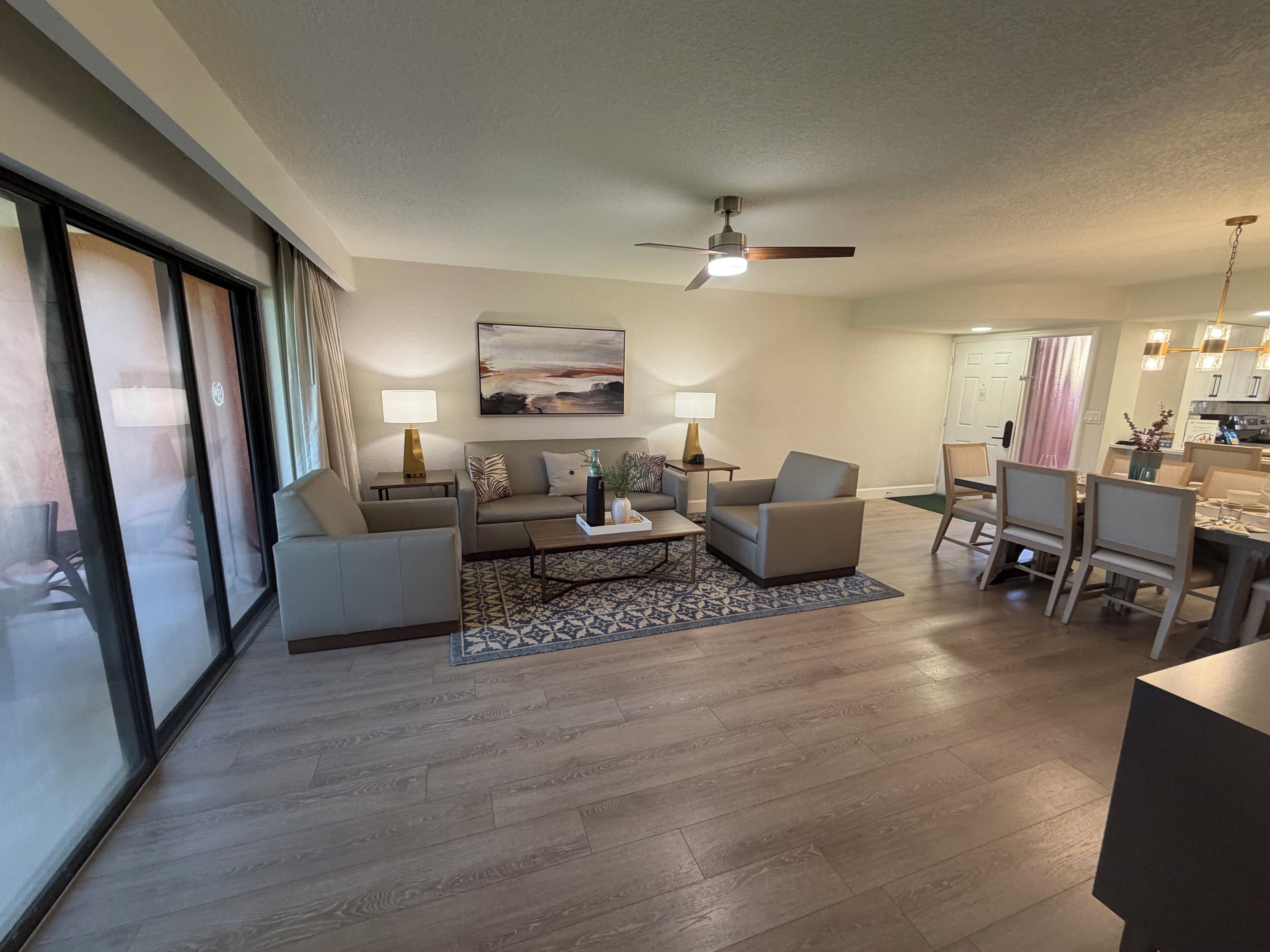 A modern living room with a sofa, armchairs, a coffee table, and a dining area with chairs and a table.