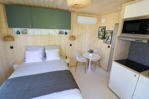 A bedroom with a bed, a small dining table, and a kitchenette.