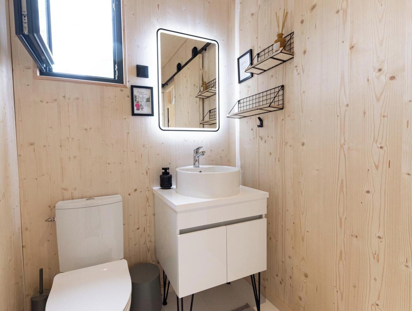 A modern bathroom with a white sink, mirror, and toilet.