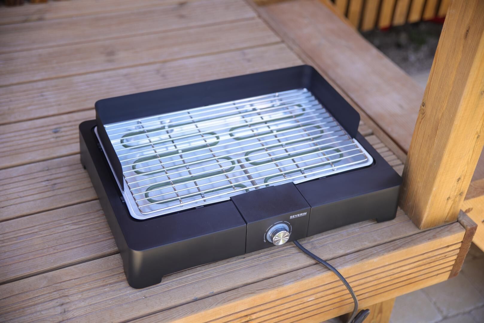 En bærbar elgrill med en kontrolknap på en træterrasse.