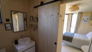 Ett rum med träpanel på väggarna, en säng, ett vitt handfat och en spegel.