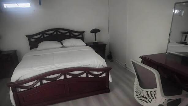 Un dormitorio con cama, mesita de noche, lámpara, escritorio, silla y espejo.