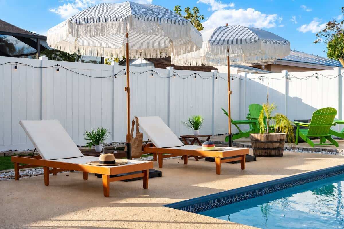 Zona de piscina con sillones de descanso, sombrillas y una pileta.