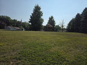 A grassy field with a gazebo and a flagpole.