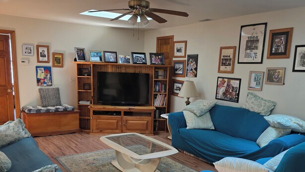 A living room with a ceiling fan, a television, a bookshelf, a sofa, and a coffee table.