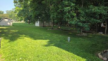 A grassy area with trees, a shed, and a picnic table.
