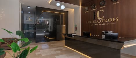 A hotel reception desk with a modern design, a clock, and a sign for 'Hotel Colorres.'
