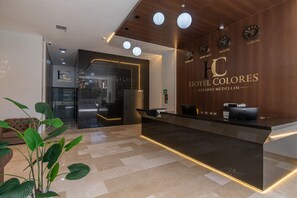 A hotel reception desk with a modern design, a clock, and a sign for 'Hotel Colorres.' - Hotel Colores Estadio (Medellín)
