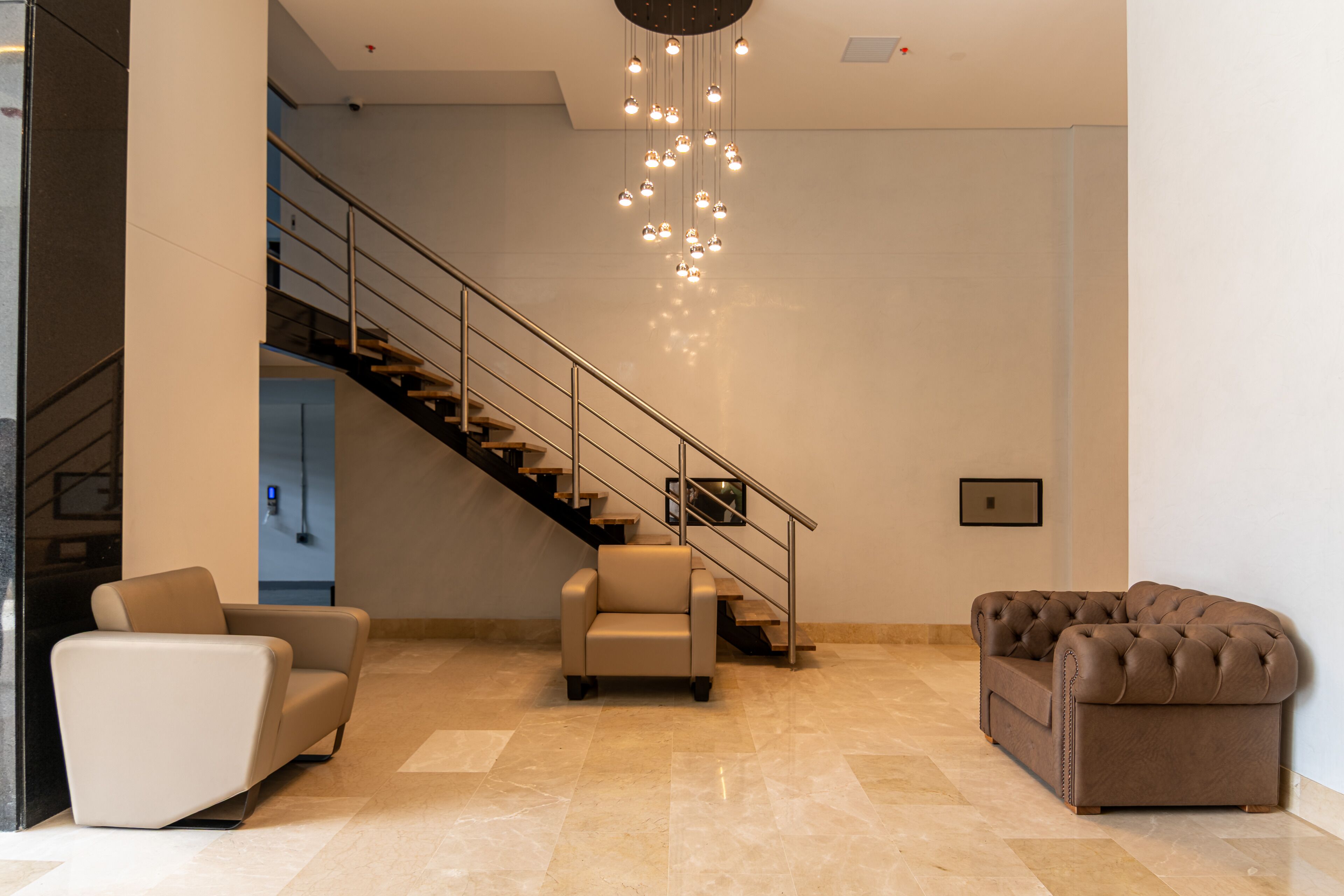 Ein modernes Interieur mit Treppe, zwei Sofas und einem Kronleuchter.