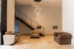 A modern interior with a staircase, two sofas, and a chandelier.