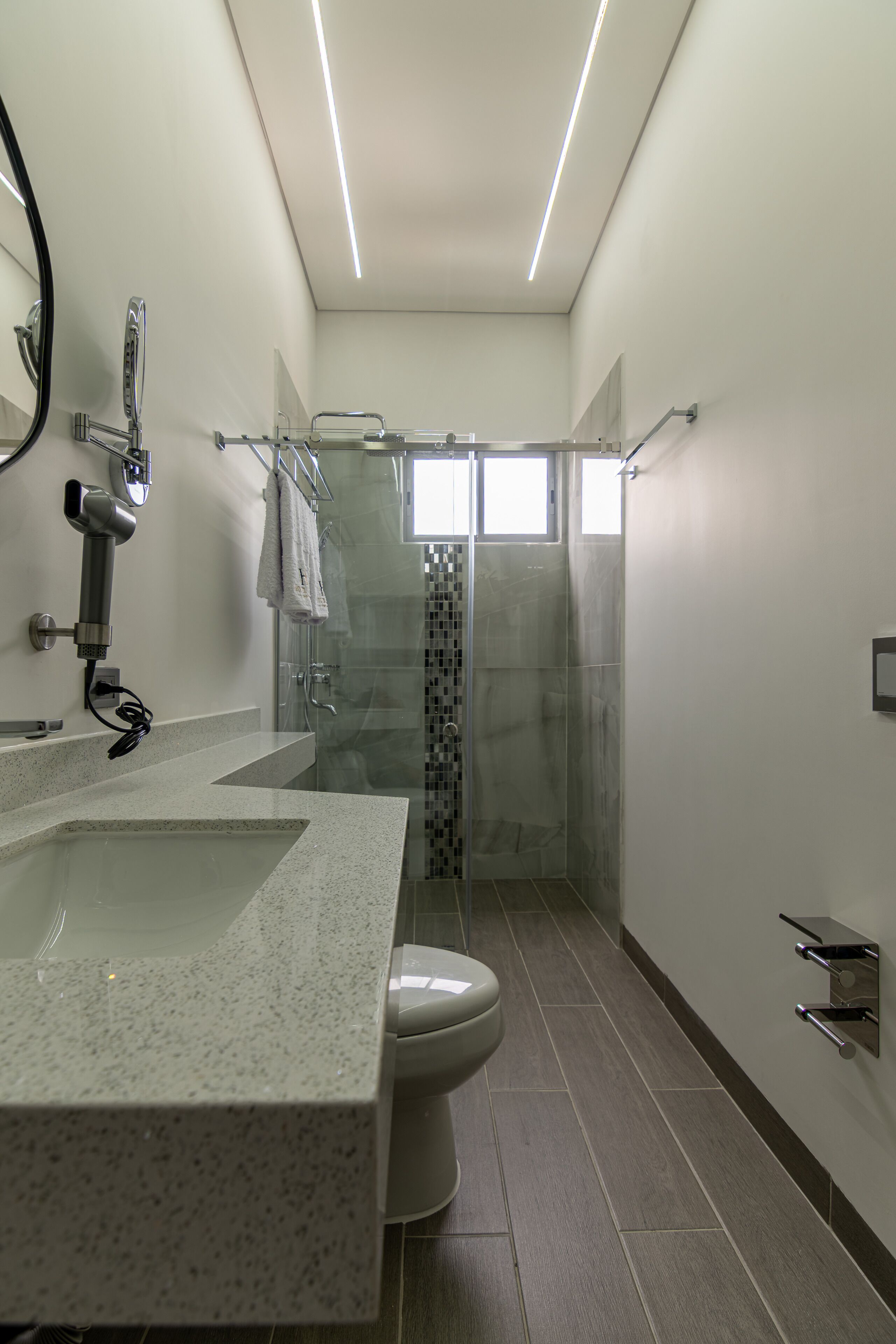 Un baño moderno con lavamanos grande, inodoro y cabina de ducha con mampara de vidrio.