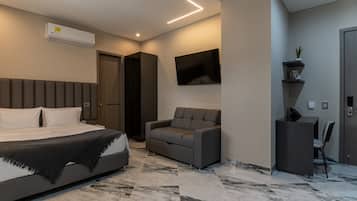 Ein modernes Schlafzimmer mit Bett, Sofa, Fernseher und Schreibtisch.