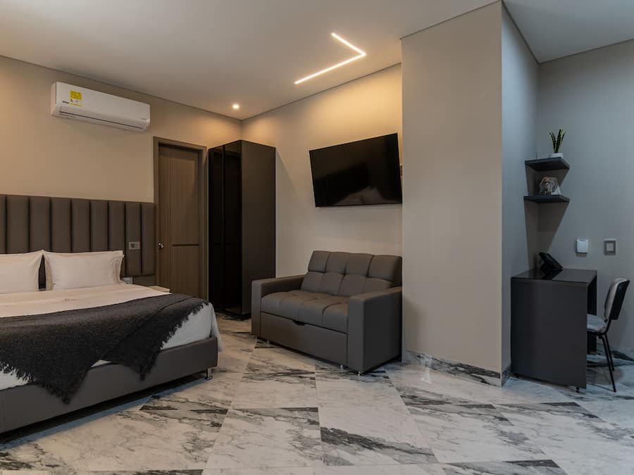 Un dormitorio moderno con cama, sofá, televisor y escritorio.