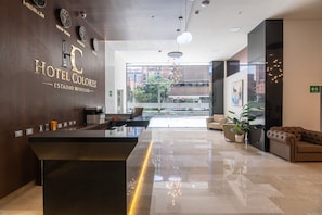 Een hotel receptie met een modern ontwerp, inclusief een receptiebalie, een zithoek en grote ramen met uitzicht over de stad.