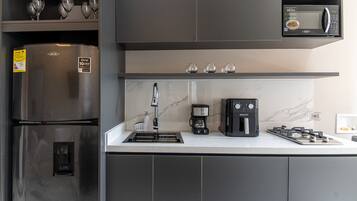 Une cuisine moderne équipée d’un réfrigérateur en acier inoxydable, d’un four à micro-ondes encastré, d’une machine à café et d’une cuisinière à gaz.