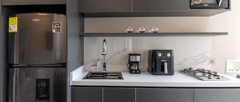 A modern kitchen with a stainless steel refrigerator, a built-in microwave, a coffee maker, and a gas stove.