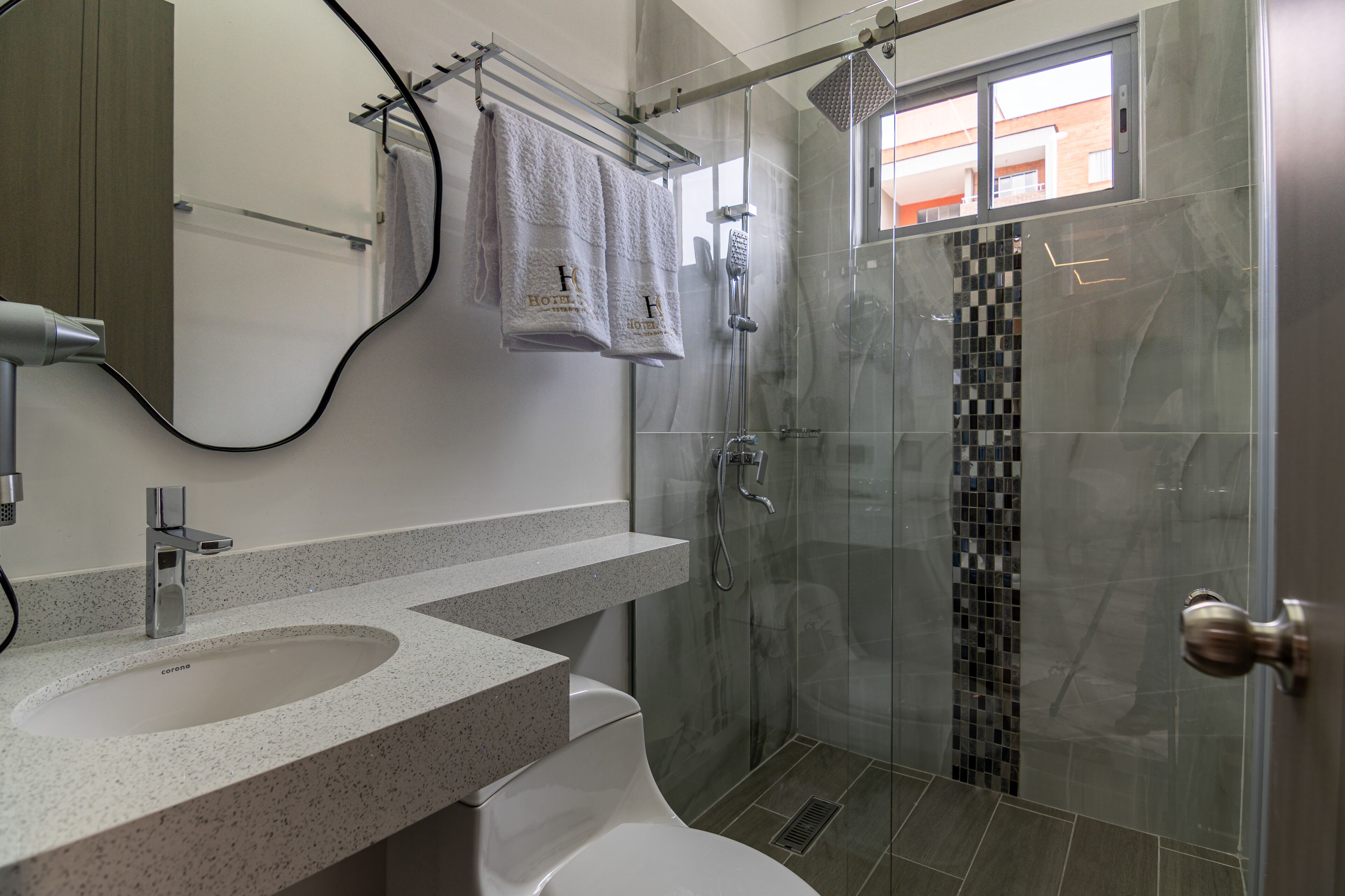 Een moderne badkamer met een douchecabine van glas, een wastafel met spiegel en een handdoekrek.