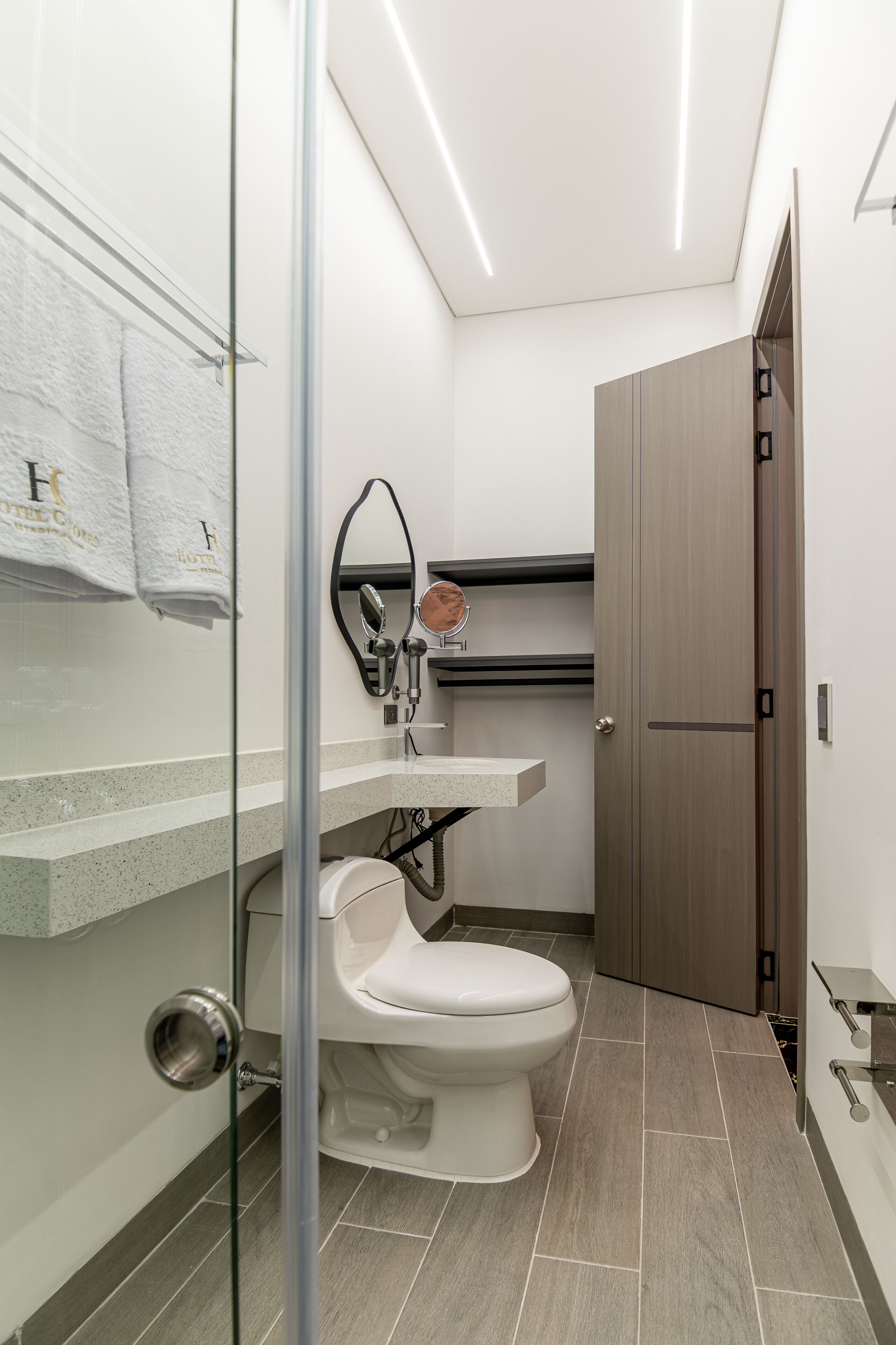 Ein modernes Badezimmer mit Toilette, Waschbecken mit Spiegel und einer Duschkabine.