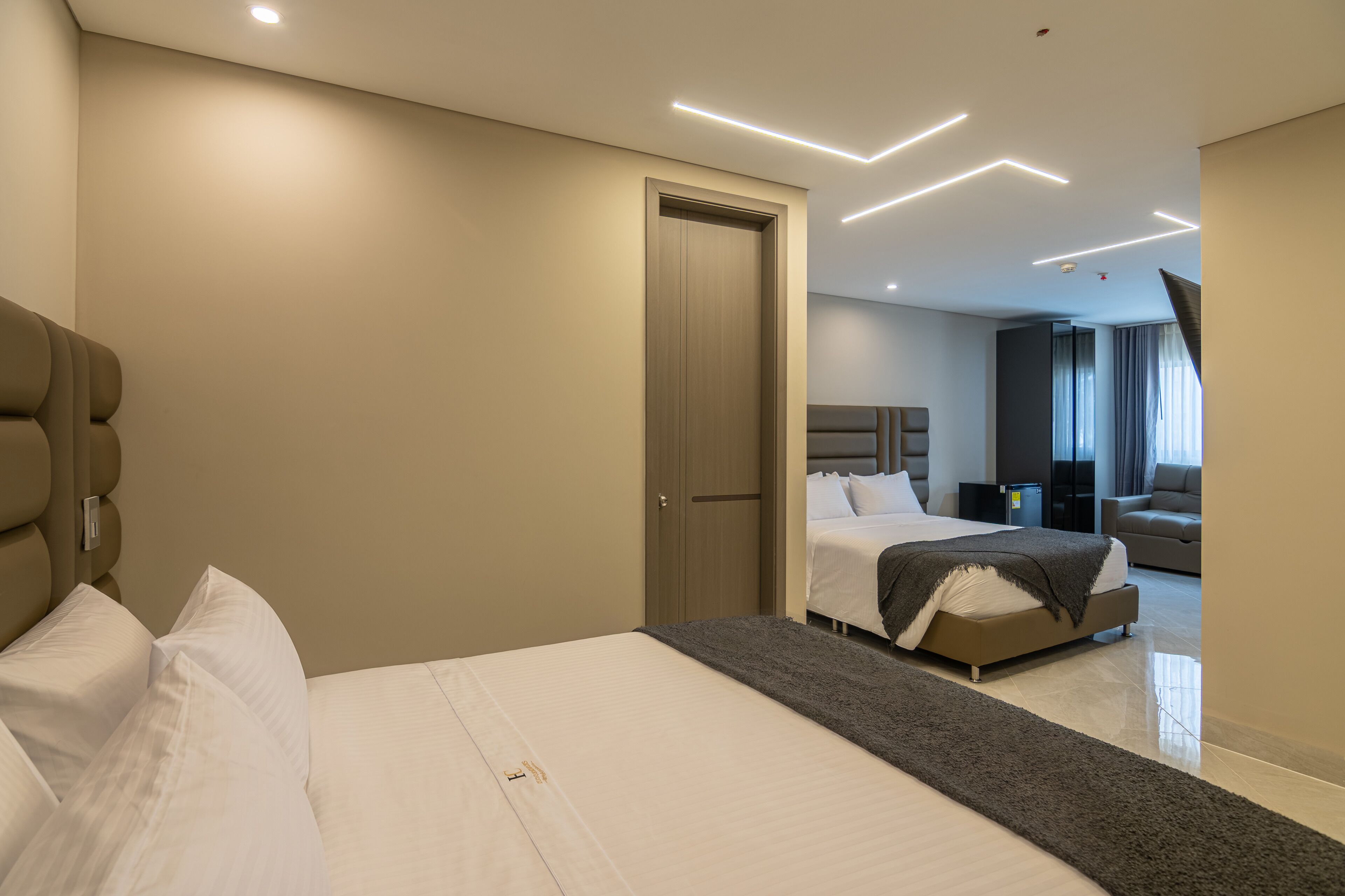 Habitación de hotel moderna con una cama grande, una zona de estar separada y vistas a la ciudad.