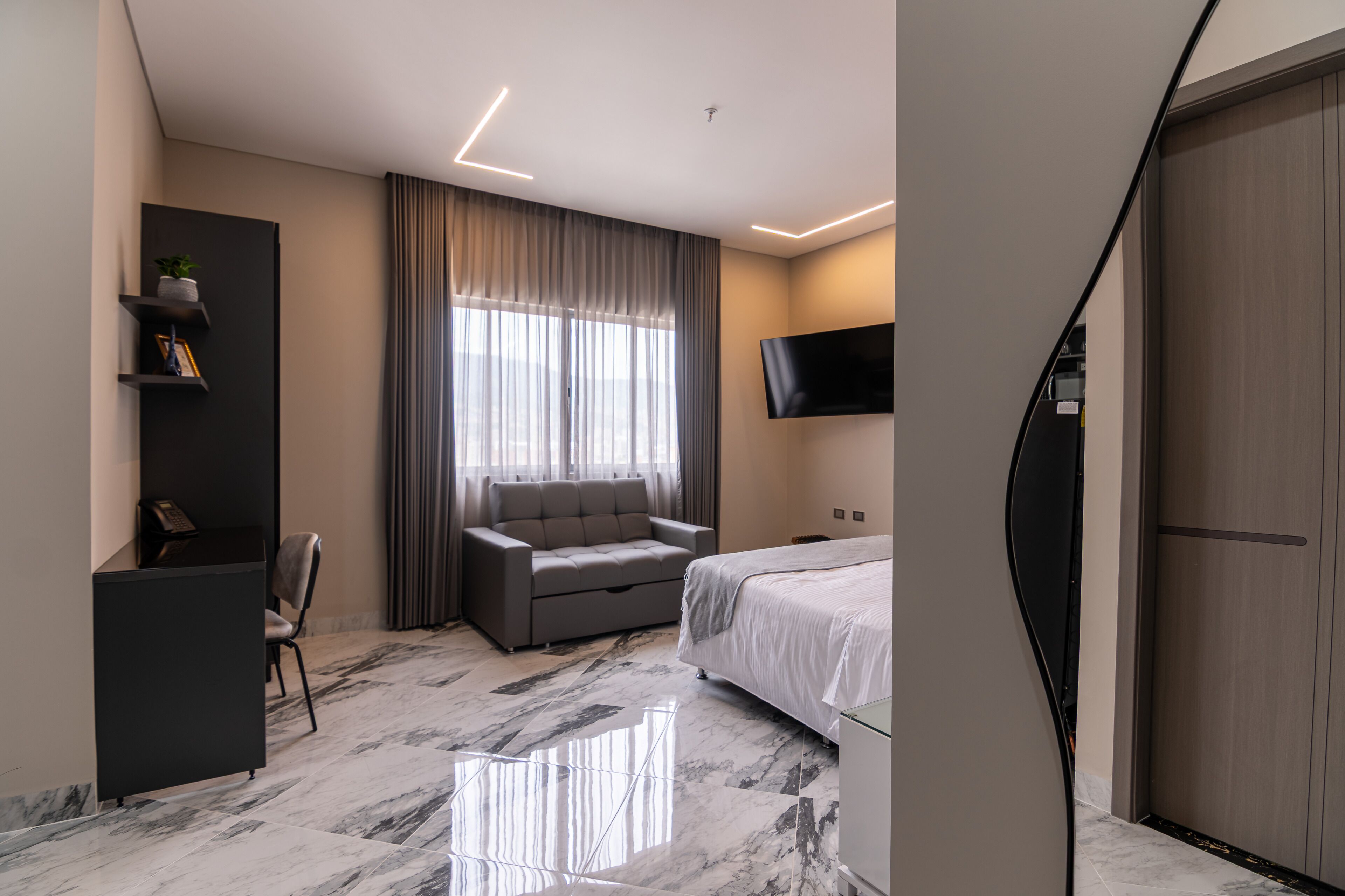 Une chambre d’hôtel moderne équipée d’un canapé, d’un lit, d’un bureau et d’une télévision.